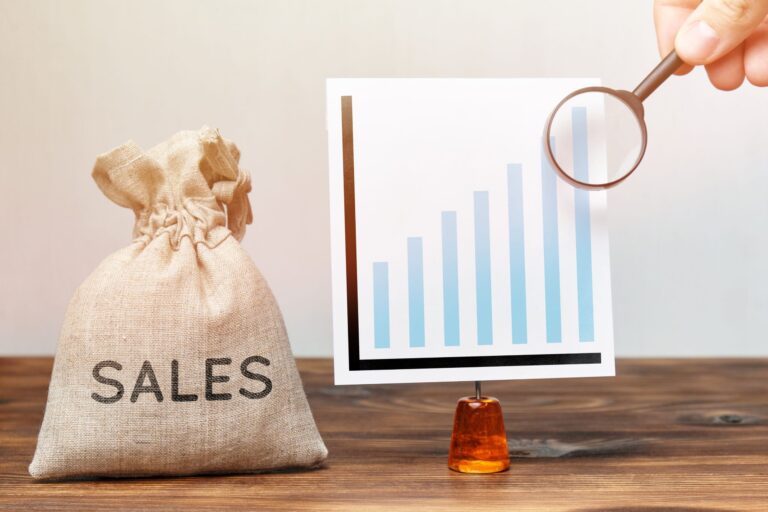 Sales growth chart with money bag and magnifying glass